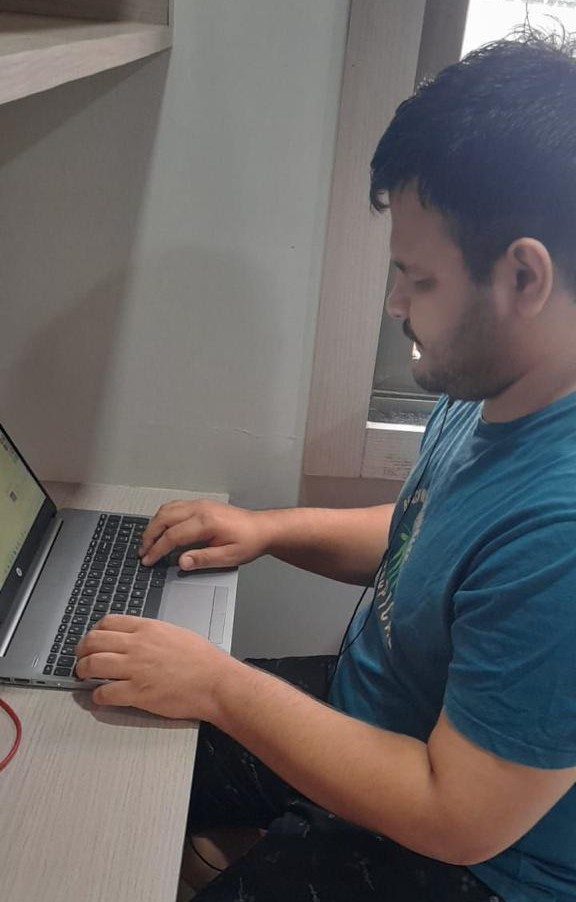 Aakash Mishra sitting on the chair and using a laptop.