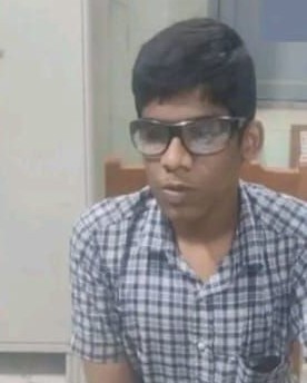Anandh, wearing his school uniform sitting on a chair.
