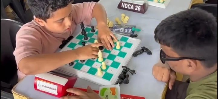 Children with visual impairments are playing chess at the competition, focusing intently on their boards and using tactile chess sets and timers.