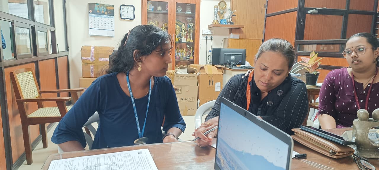HTBF staff interacting with a student during the scholarship drive, reviewing out application forms at a desk.