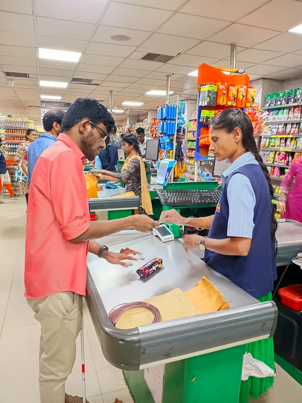 A visually impaired student making a payment at a general store.